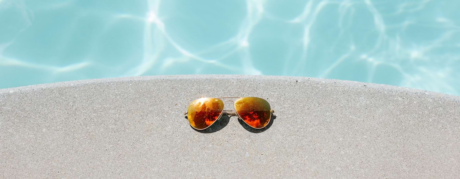 sunglasses rest on pool's edge