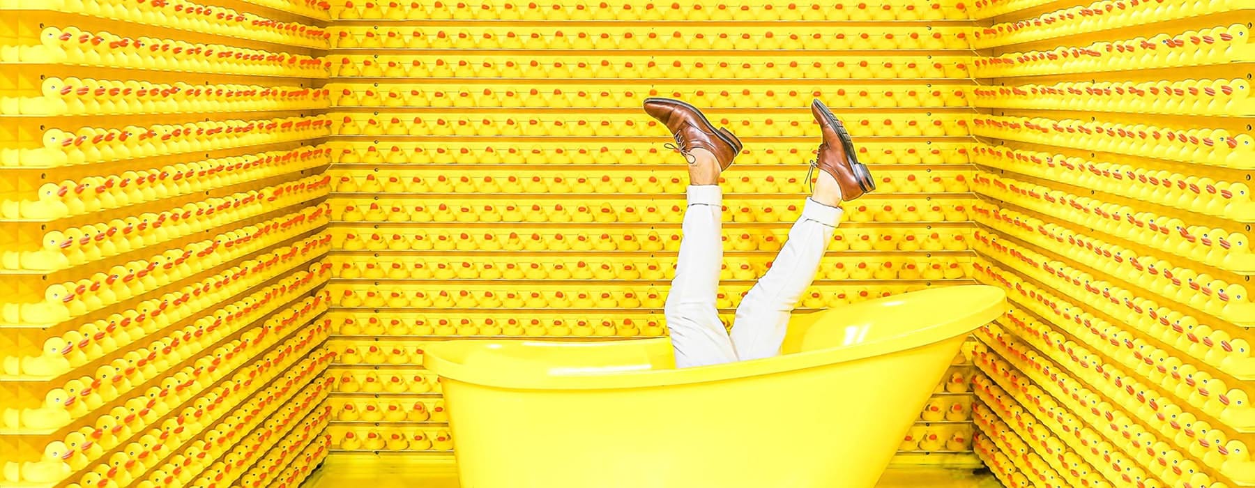 woman's legs stick out of yellow bathtub surrounded by yellow walls